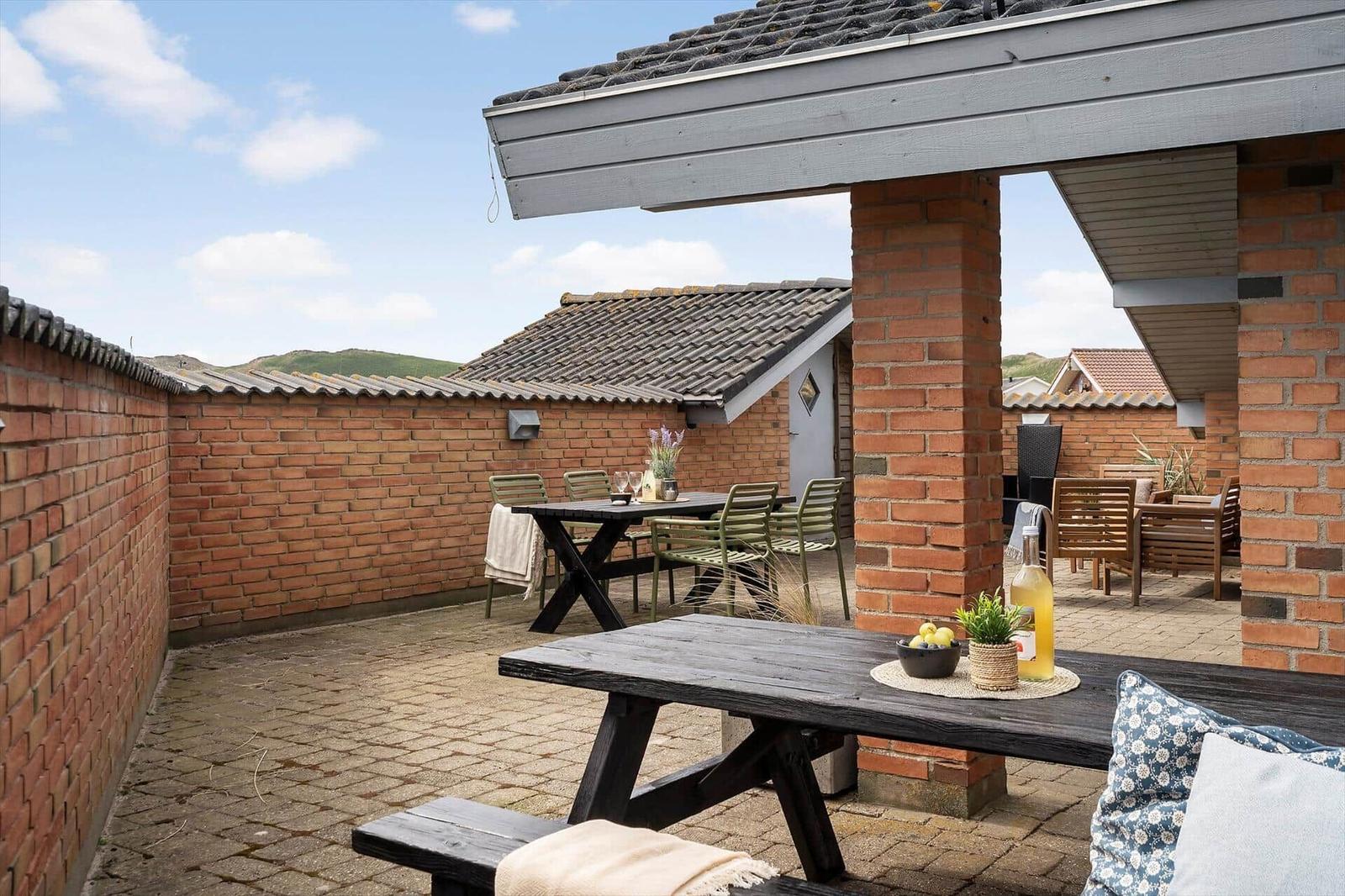 Terrasse mit Tischen, Stühlen und Sicht auf Hügel.