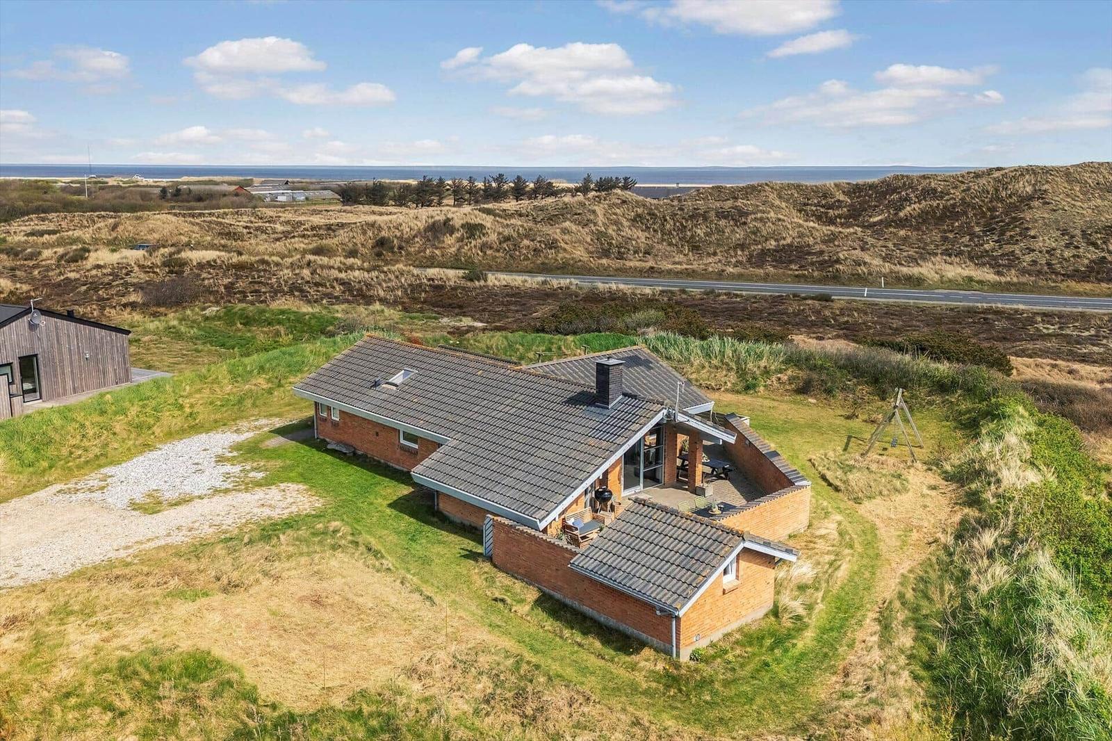 Haus mit Terrasse und Blick auf Dünen und Meer.