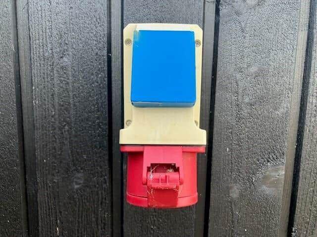 Blauer und roter Stecker an einer dunklen Holzwand.