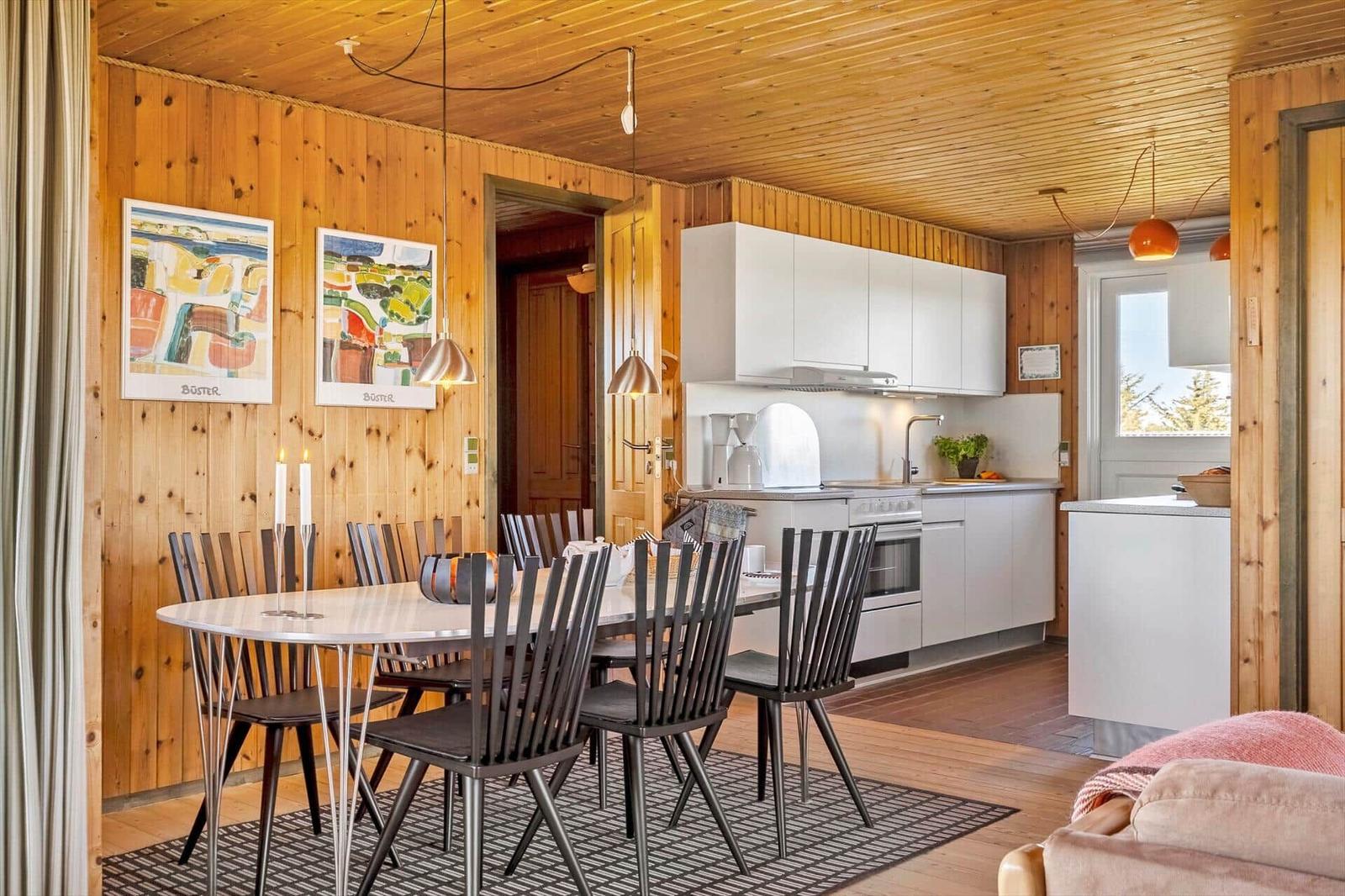 Essbereich mit Tisch, Stühlen und Küchenzeile in Holzhaus.
