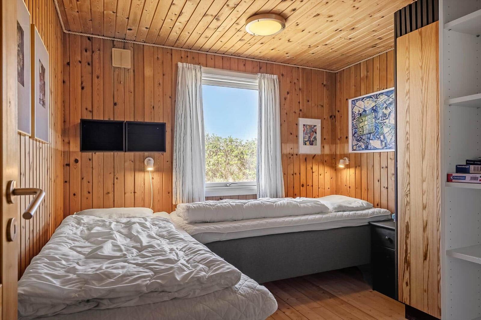 Zwei Betten in einem Holzraum mit Fenster und Wandbildern.