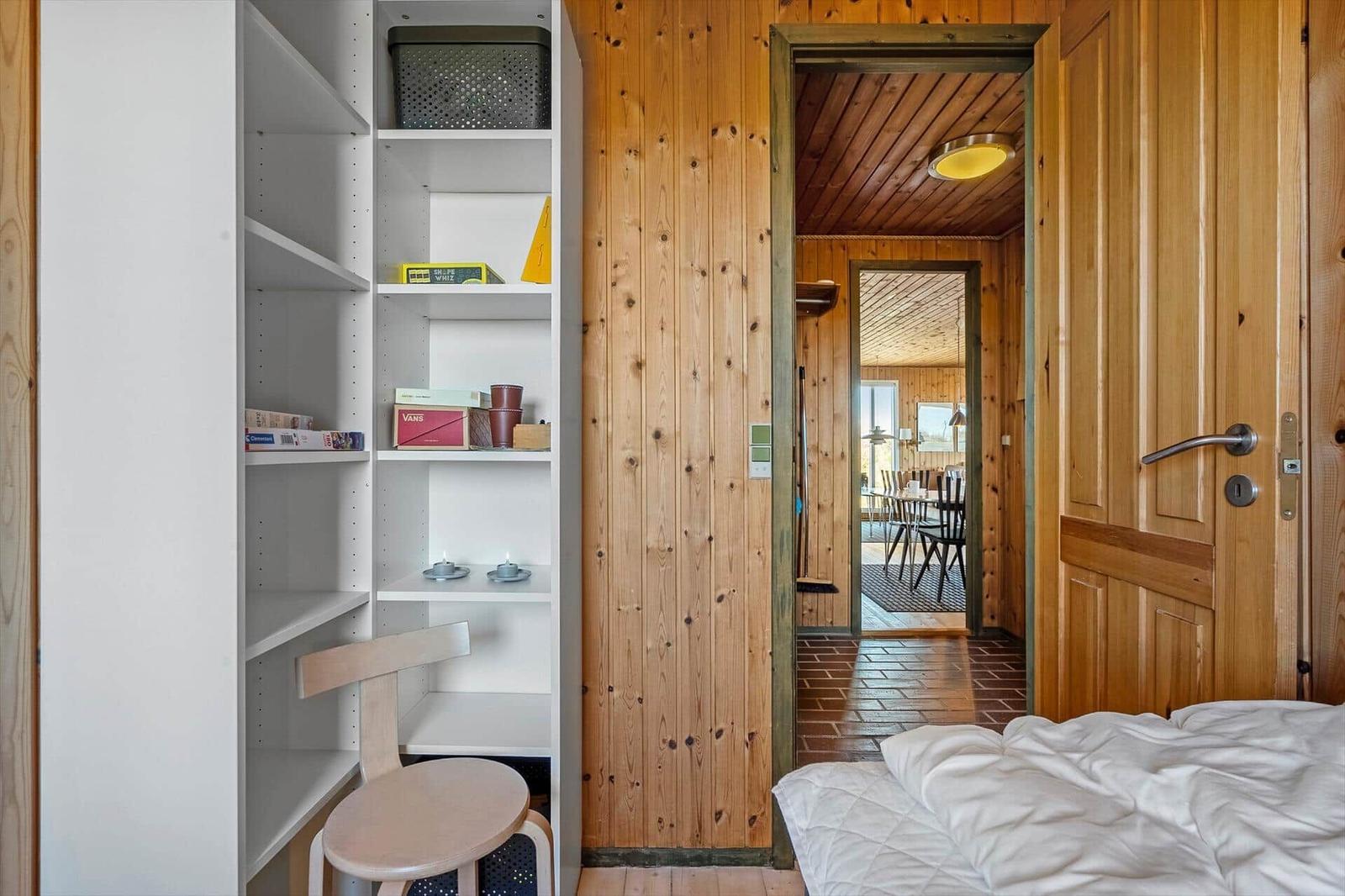 Schlafzimmer mit weißen Regalen und Blick in das Esszimmer.