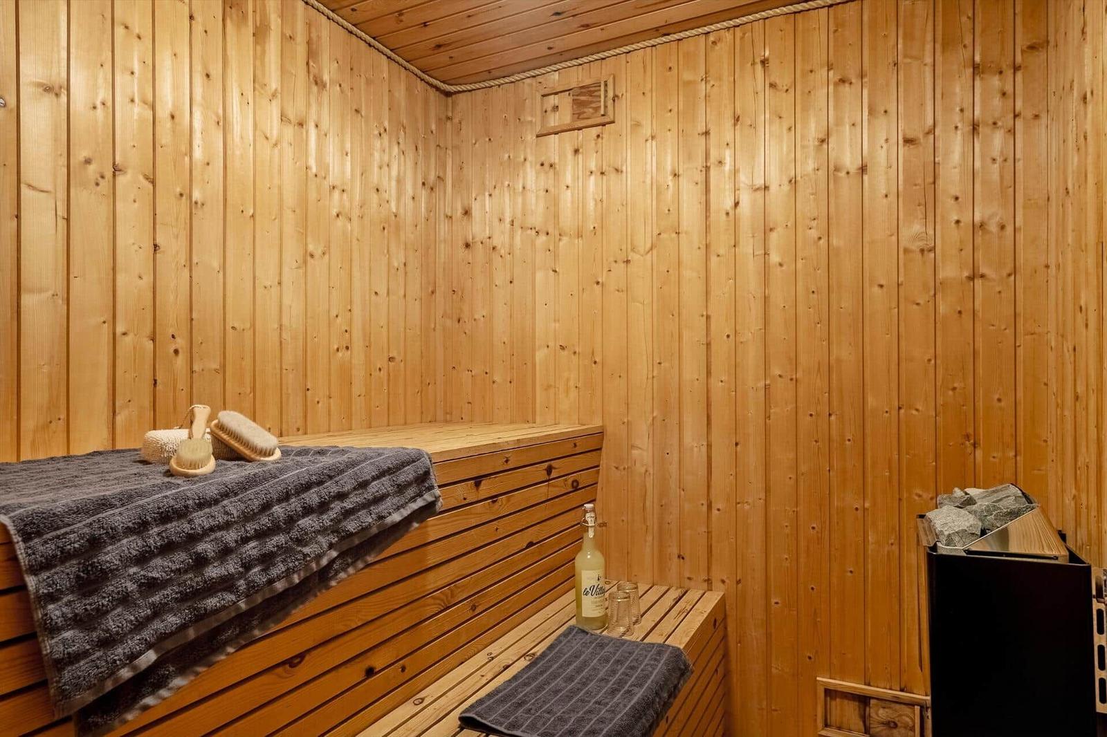 Sauna mit Holzwand, Sitzbank, Handtuch und Saunasteine.