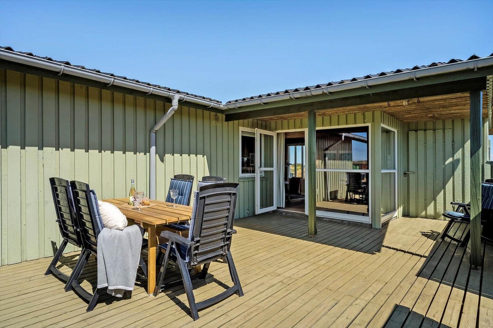 Terrasse mit Holztisch, Stühlen und Blick ins Haus.