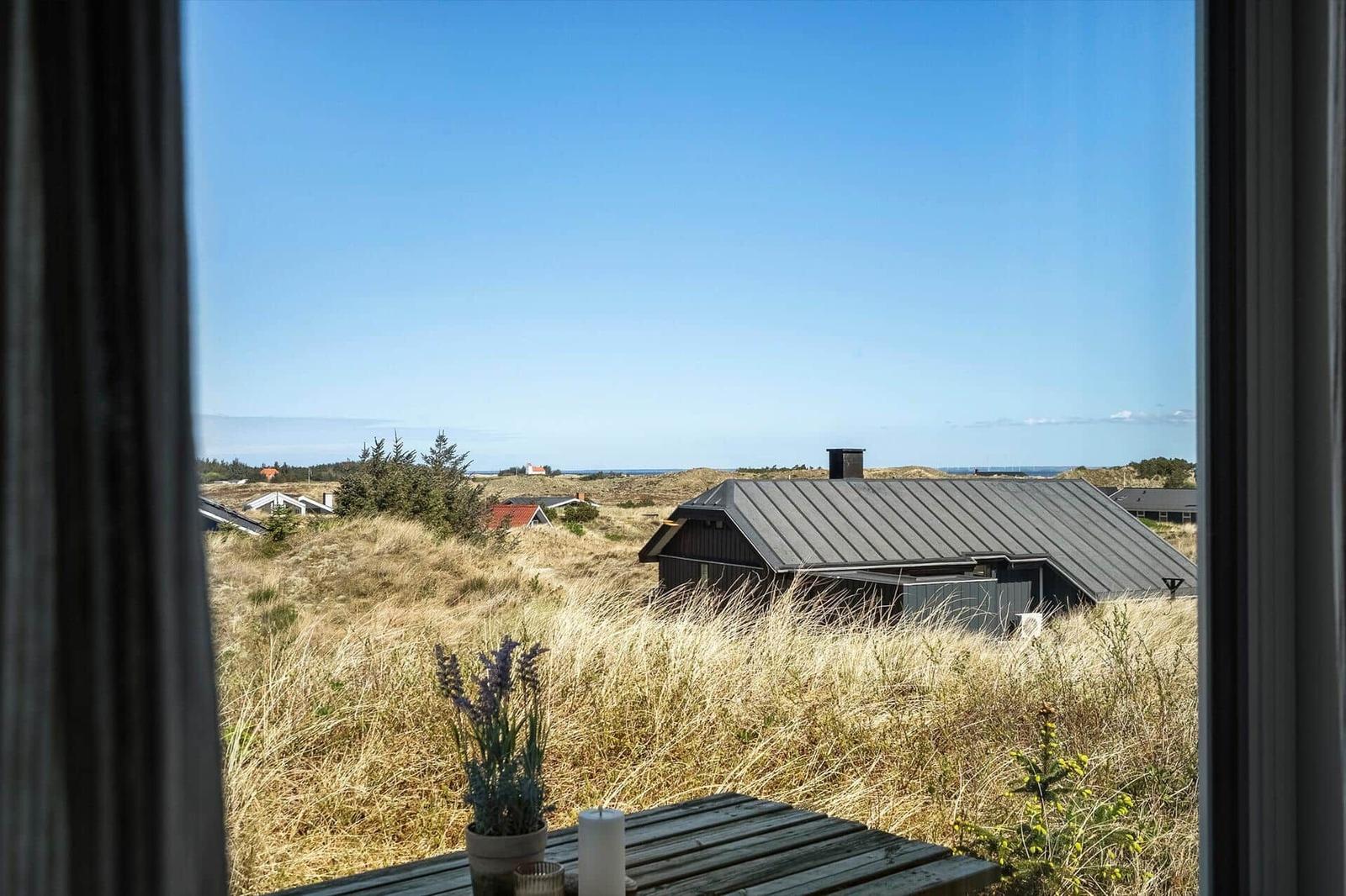 Von innen aus gesehen, Blick auf eine Hütte in der Heide mit blauem Himmel.