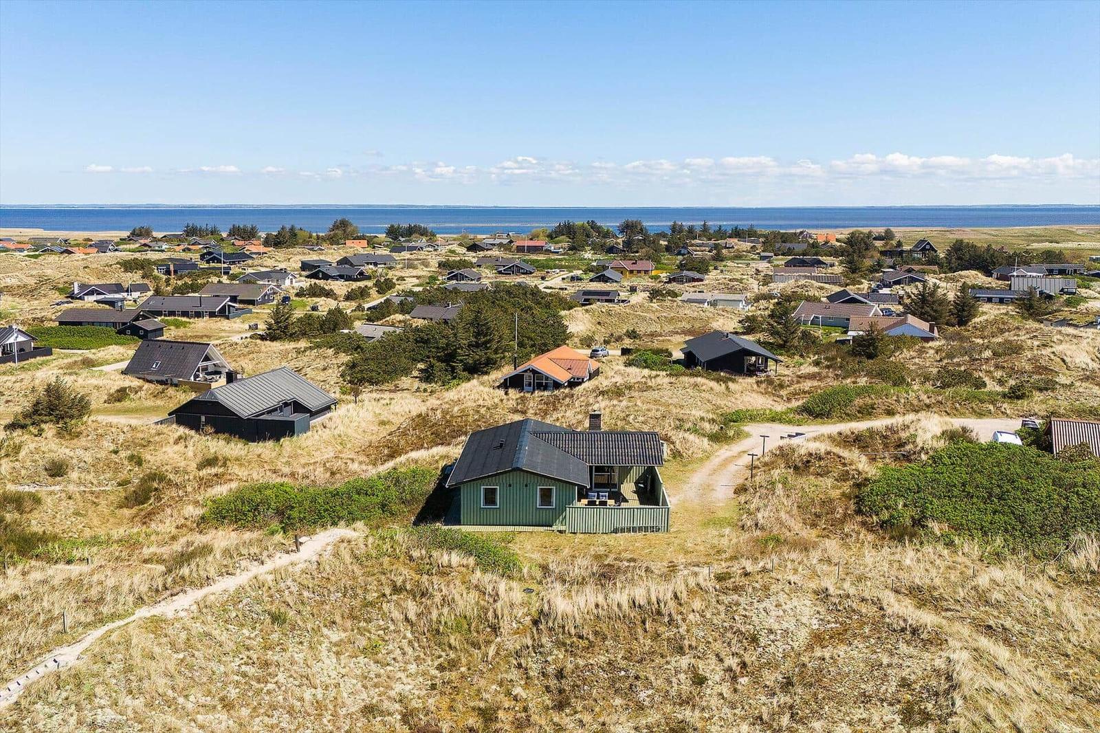 Grünes Haus auf Dünen mit Blick auf Meer und Ferienhäuser