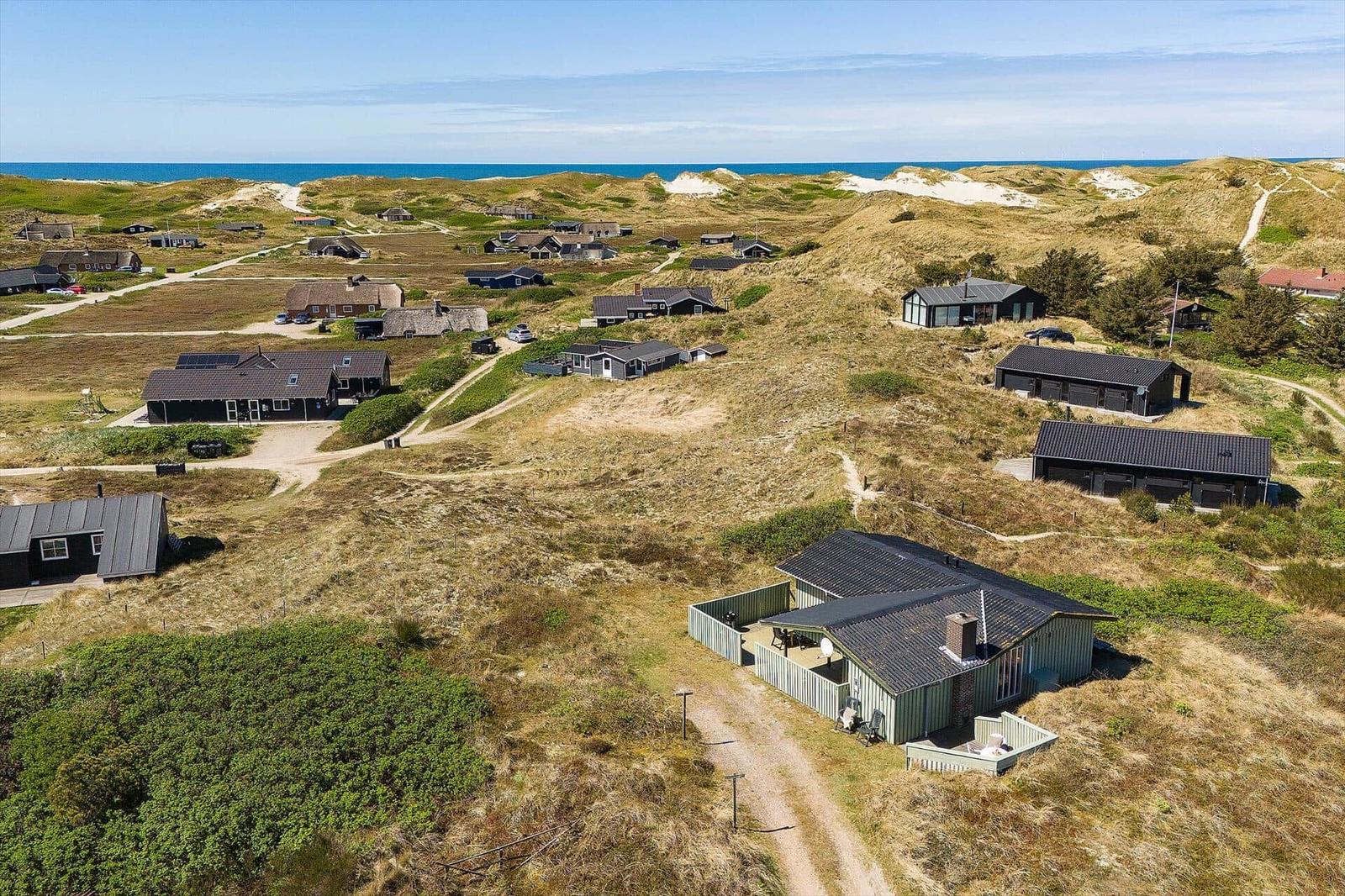 Haus mit Terrasse auf Dünenlandschaft, Blick auf das Meer.