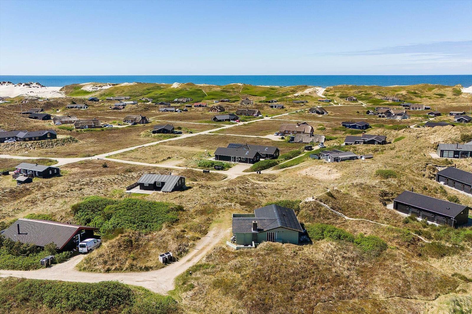 Aussicht auf Strandvillen auf Dünen mit Meer im Hintergrund.