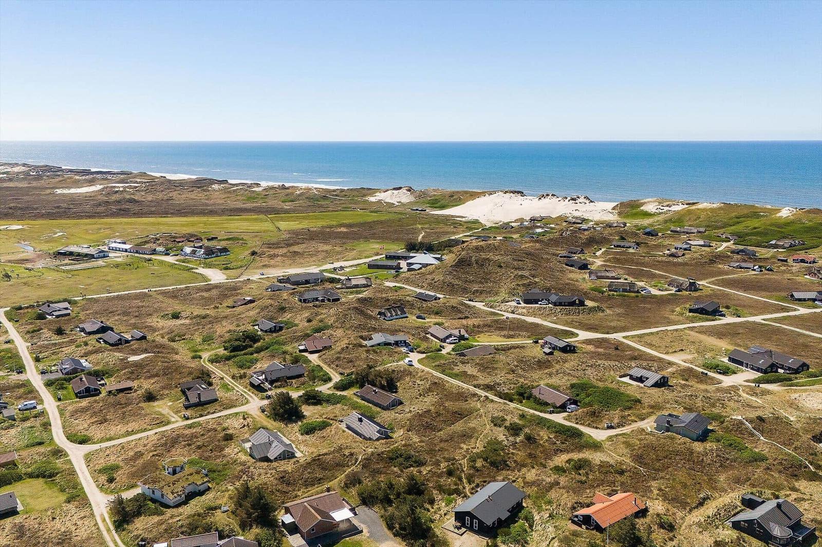 Aerial view of coastal property with houses on dunes near the sea.
