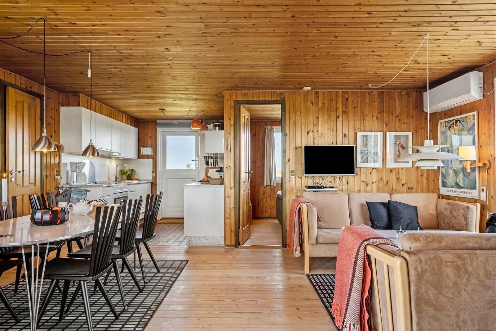 Wohnung mit Holzwand, Küche, Essbereich und Wohnzimmer mit Sofa und Fernseher.