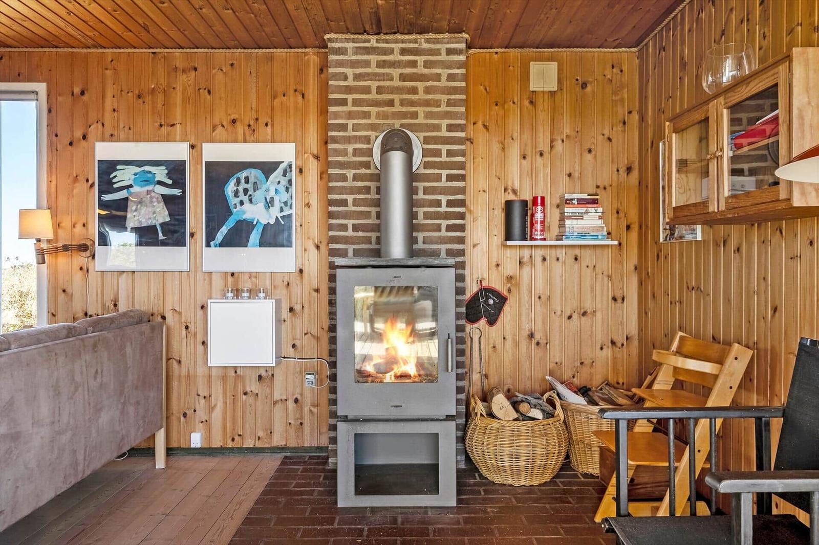 Raum mit Kamin, Holzwand und Sofa. Bilder und Körbe sind sichtbar.