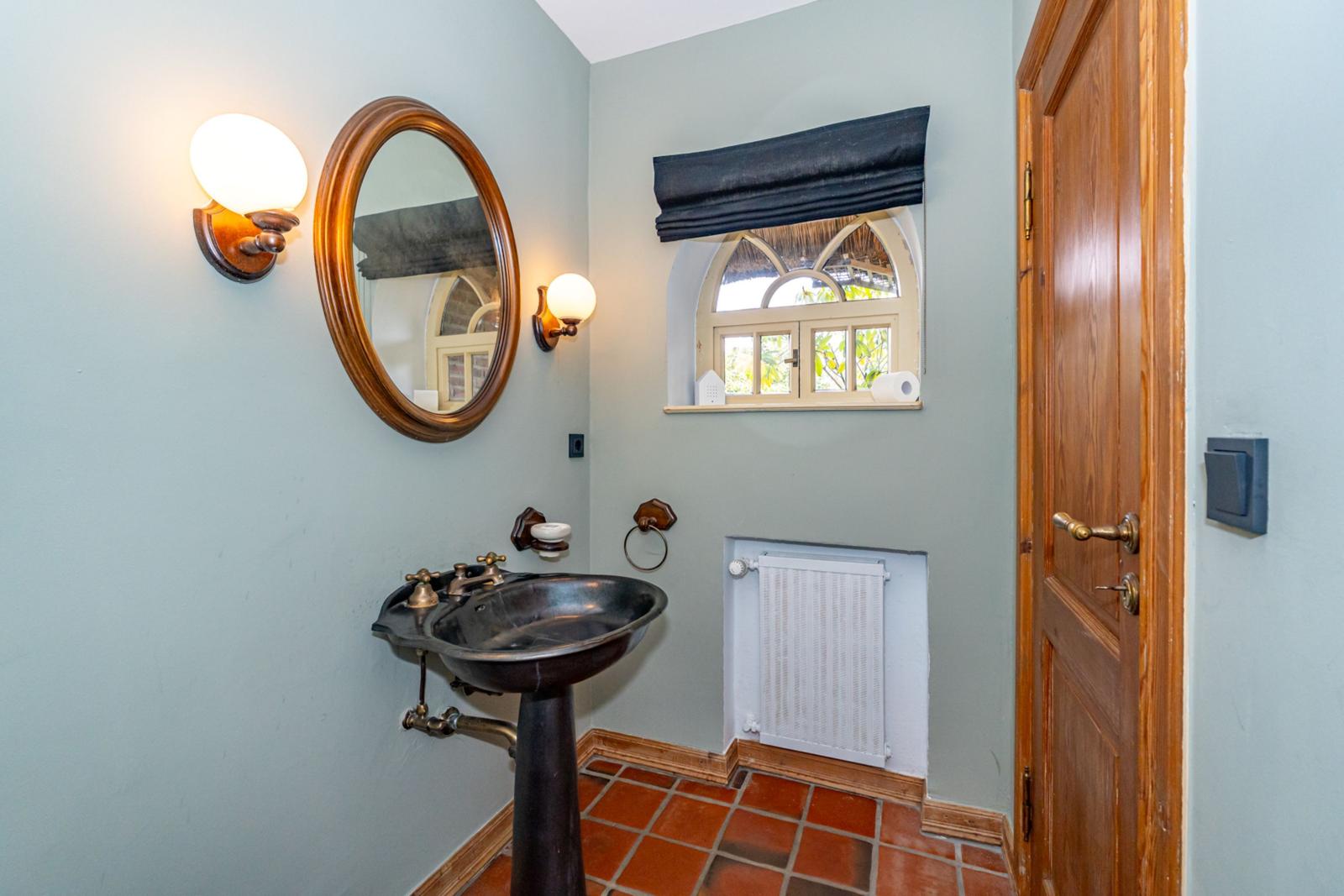 Badezimmer mit Standwaschbecken, Spiegel und Fenster.