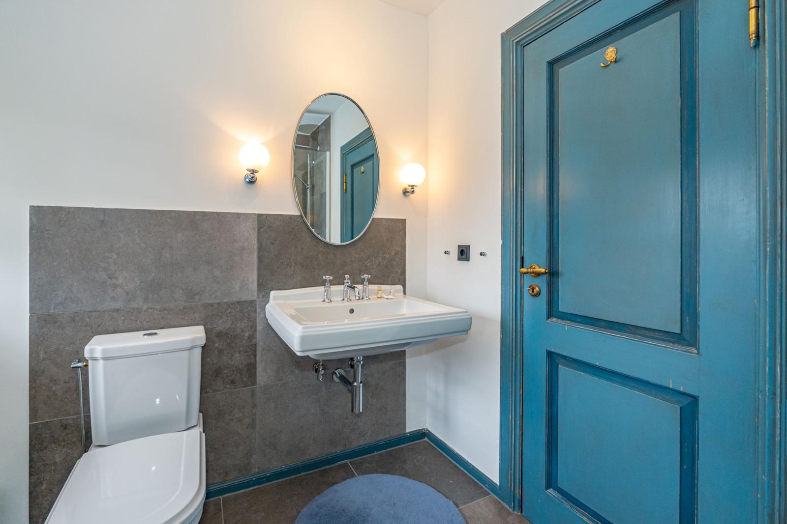 Badezimmer mit Toilette, Waschbecken und blauer Tür.
