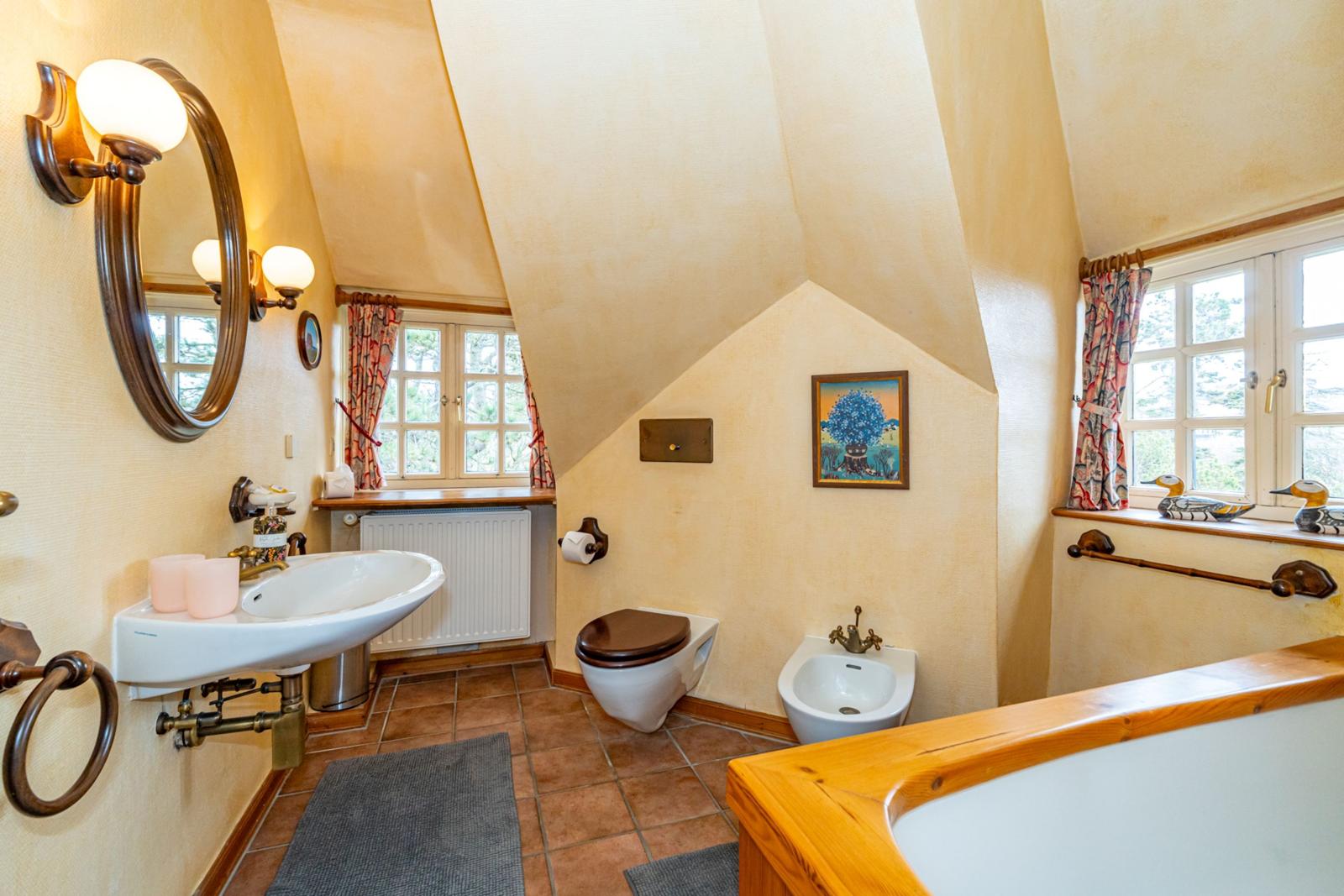 Badezimmer mit Dusche, Toilette und Waschbecken unter schrägen Decken