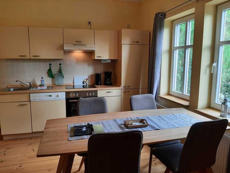 Küche mit Essbereich, Holztisch und Fenstern zur Aussicht.