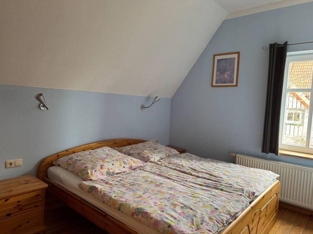 Schlafzimmer mit Doppelbett, Holzmöbel und Fenster mit Blick nach draußen.