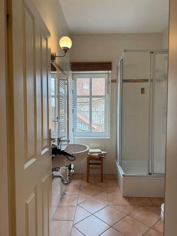 Badezimmer mit Dusche, Waschbecken und Fenster.