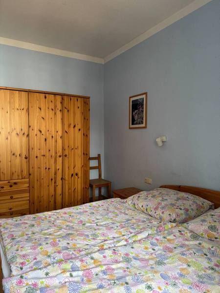 Schlafzimmer mit Bett, Kleiderschrank und Stuhl an der Wand.