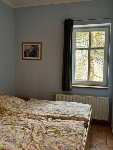 Schlafzimmer mit Bett, Fenster und Heizung.