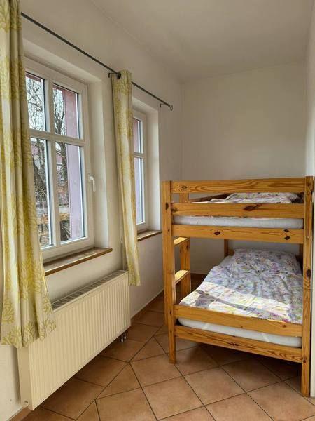 Ein Raum mit einem Holzbett und zwei Fenstern mit Vorhängen.