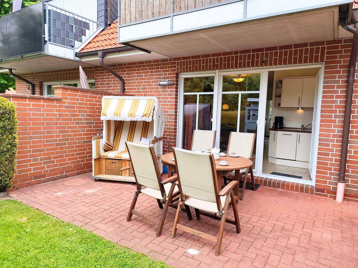 Terrasse mit Sitzgruppe, Strandkorb und Blick in die Küche.