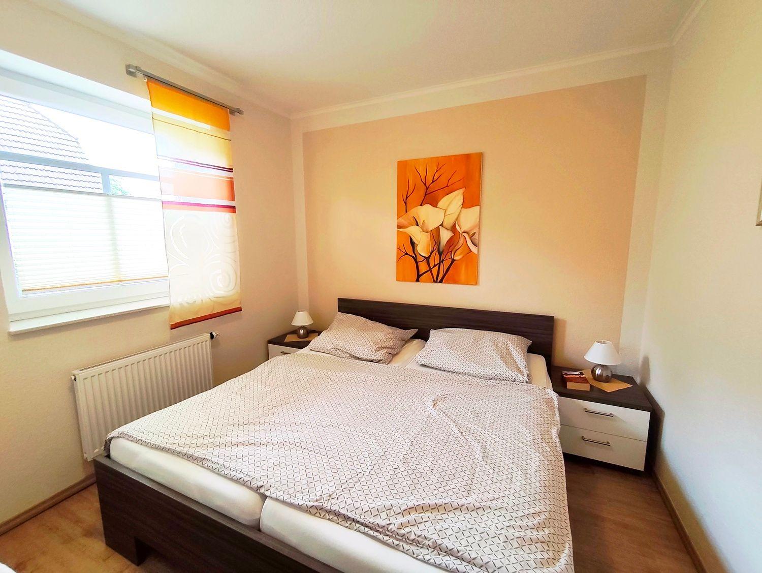 Schlafzimmer mit Doppelbett, zwei Nachttischen und Wandbild.