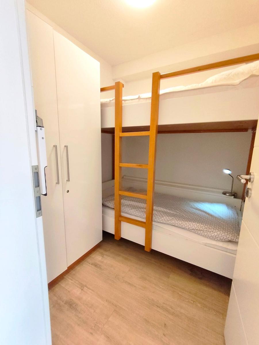 Zimmer mit Doppelstockbett, Kleiderschrank und Holzboden.
