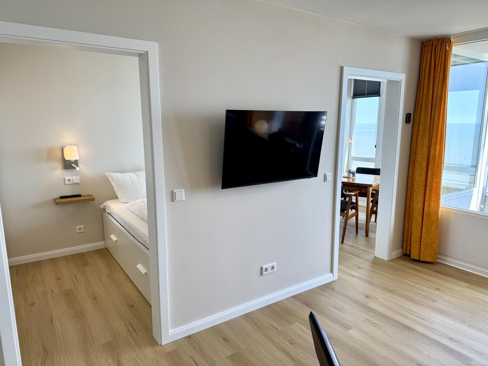 Wohnung mit Schlafzimmer, TV und Blick aufs Meer.