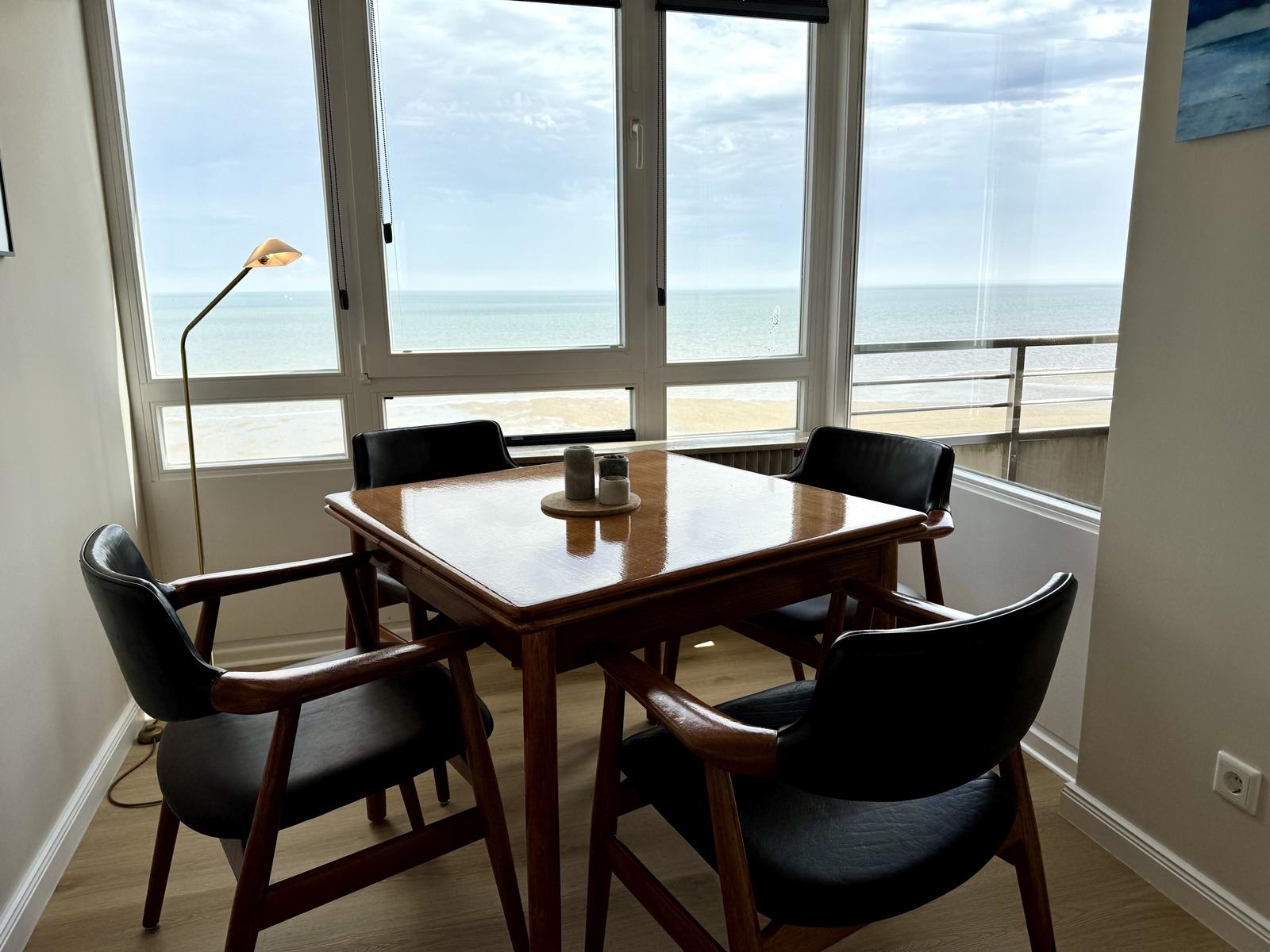 Esszimmer mit Blick aufs Meer und Holztisch mit vier Stühlen.