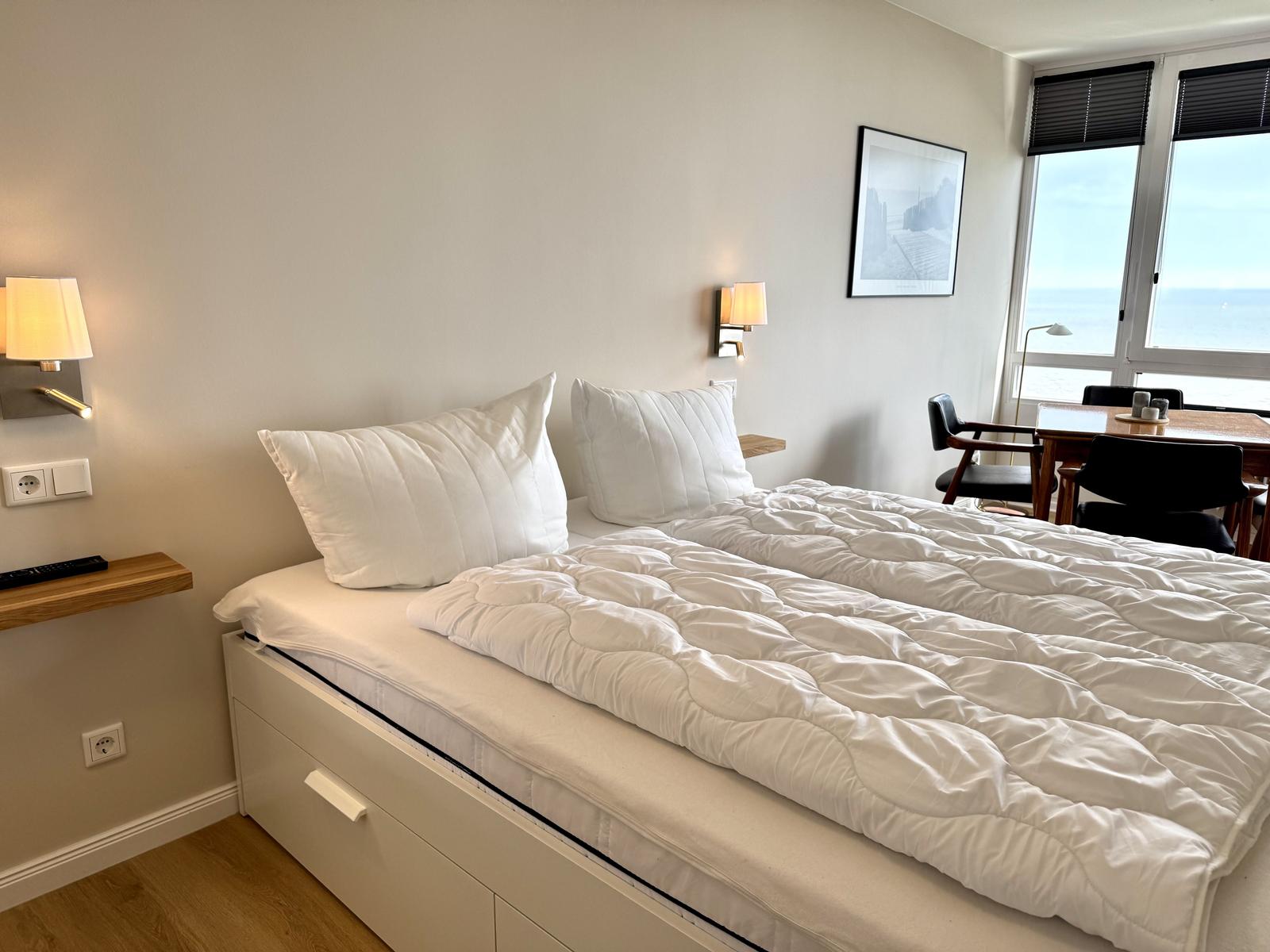 Schlafzimmer mit Bett, Tisch und Meerblick.