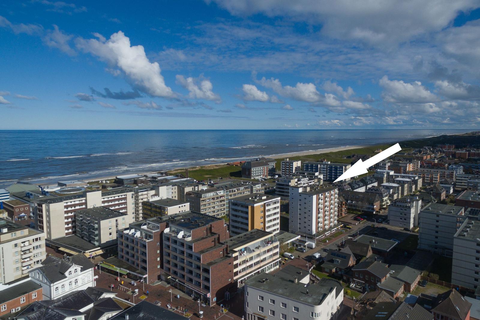 Aussicht auf Strand und Stadt mit weißen Gebäuden und blauem Himmel.
