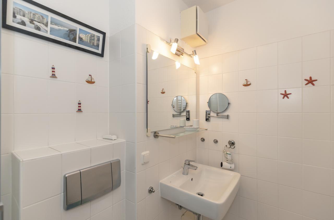 Badezimmer mit Waschbecken, Spiegel und dekorativen Wandobjekten.
