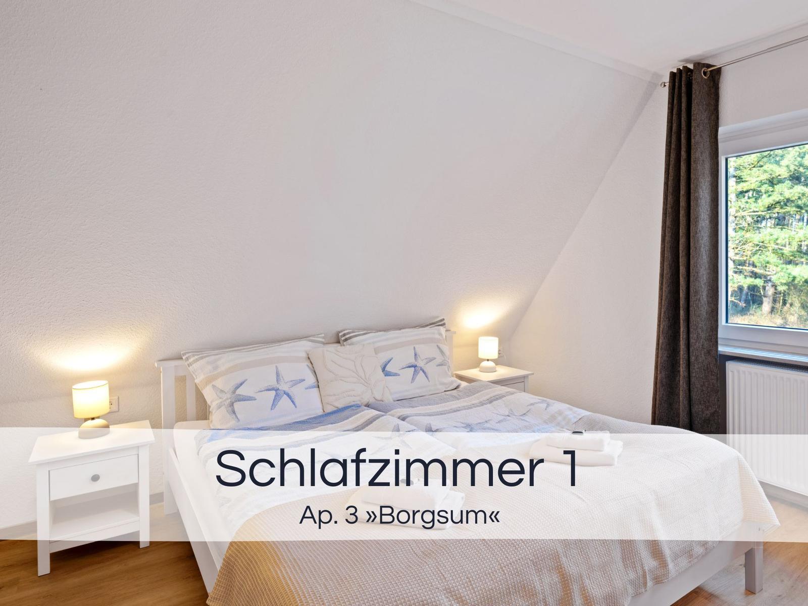 Schlafzimmer mit Doppelbett, zwei Nachttischen und Fenster mit Blick auf Wald.