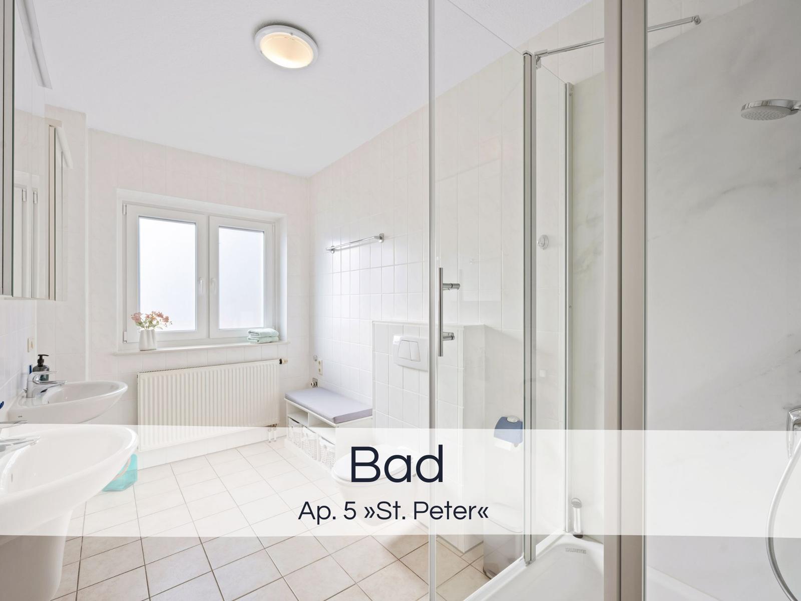 Badezimmer mit Dusche, Waschbecken und Fenster. Weiße Fliesen und moderne Einrichtung.