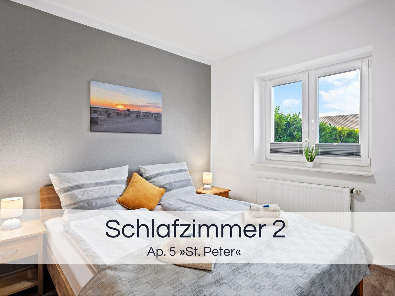 Schlafzimmer mit Bett, Nachttisch und Fenster mit Blick auf Grünflächen.