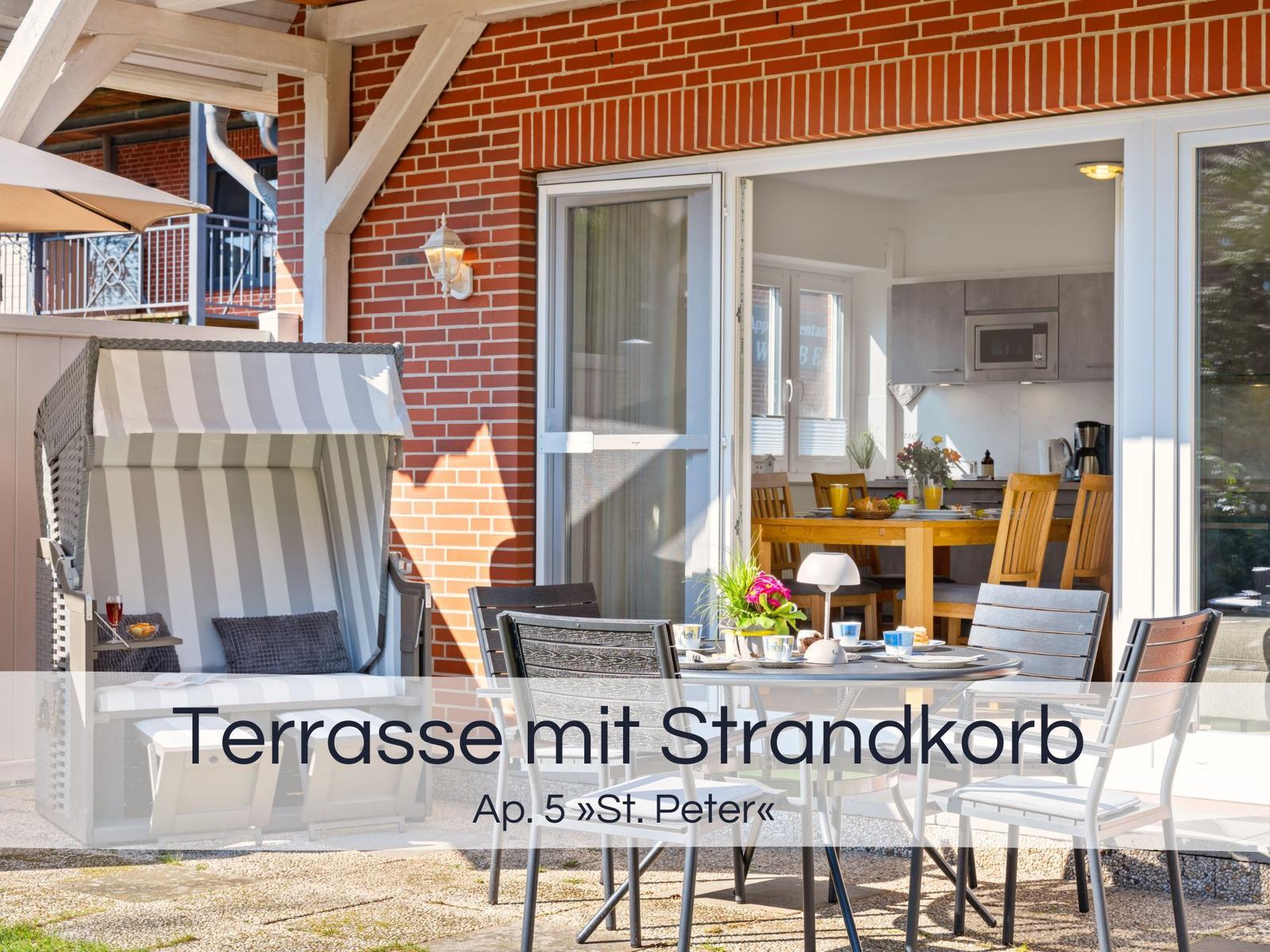 Terrasse mit Strandkorb und Esstisch. Durchgang ins Wohn- und Küchenbereich.