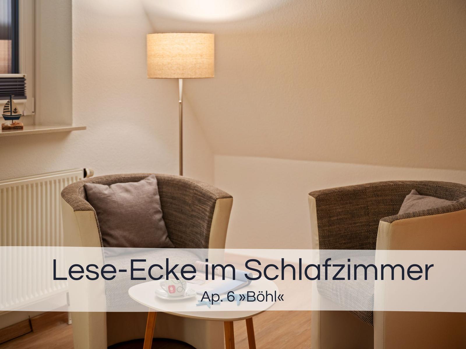 Lese-Ecke mit zwei Stühlen und Tisch im Schlafzimmer. Stehlicht und Fenster sichtbar.