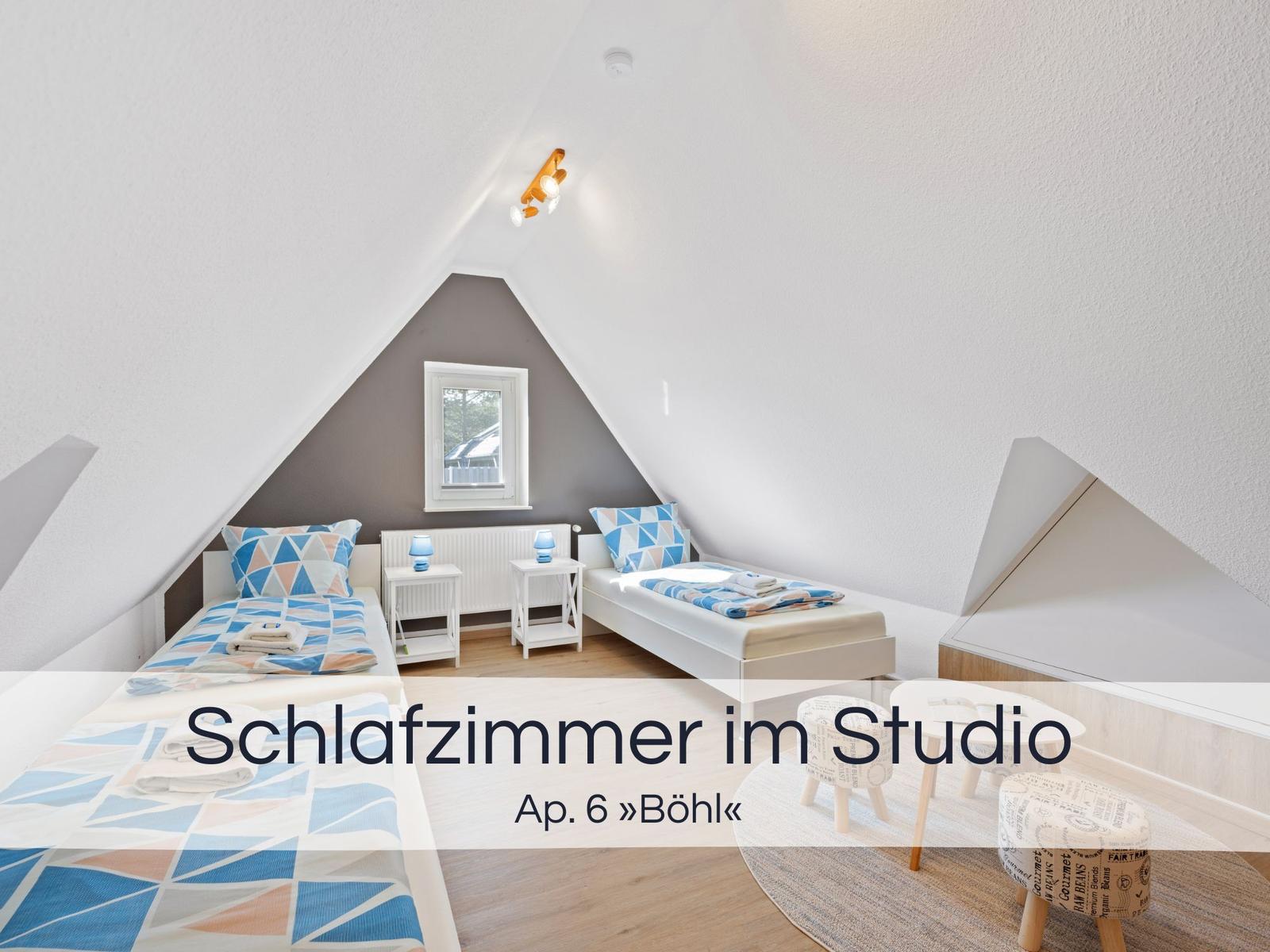 Zwei Betten im Dachgeschosszimmer mit Fenster und Nachttischen.