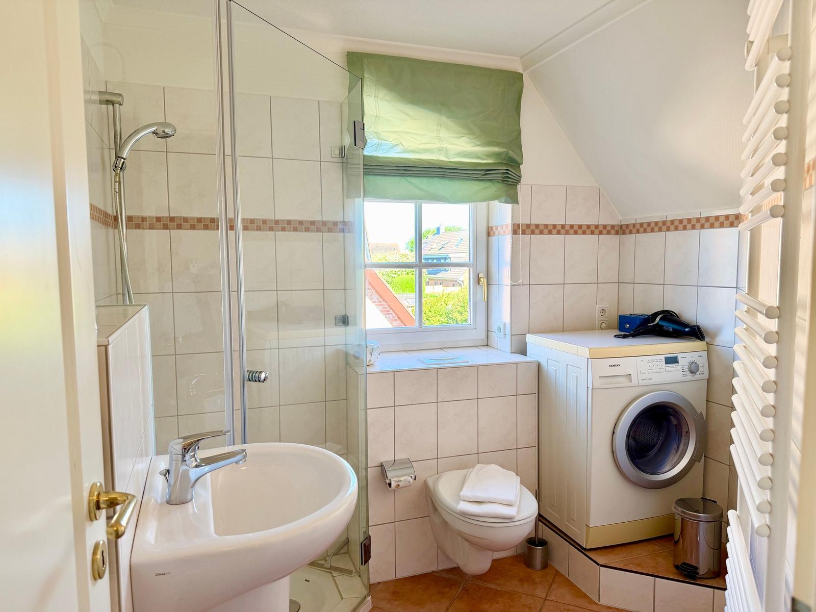Stilvolles Bad mit Dusche, eleganter Glasabtrennung und Waschmaschine mit integriertem Trockner.