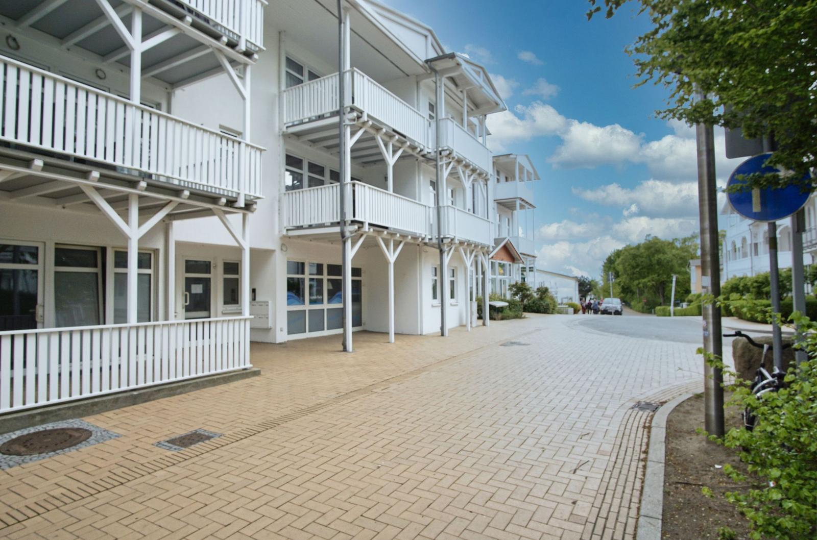 Weiße Ferienwohnung mit Balkonen und gepflastertem Weg