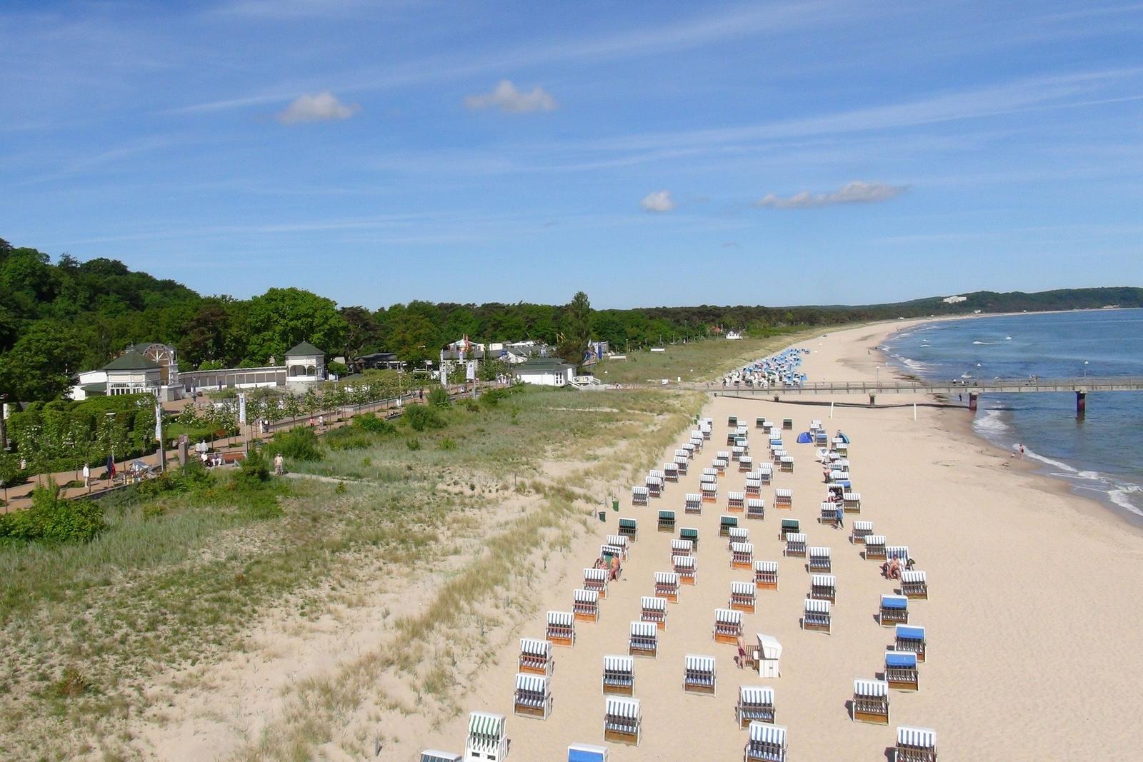 Strand mit Liegestühlen, Sandstrand und Blick aufs Meer unter blauem Himmel.
