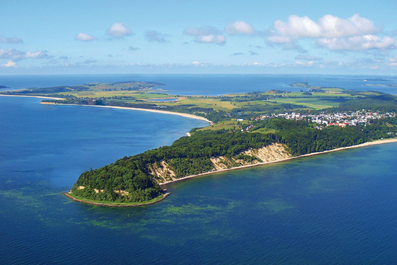 Aerial view of coastal landscape with beaches, cliffs, and green areas near water.