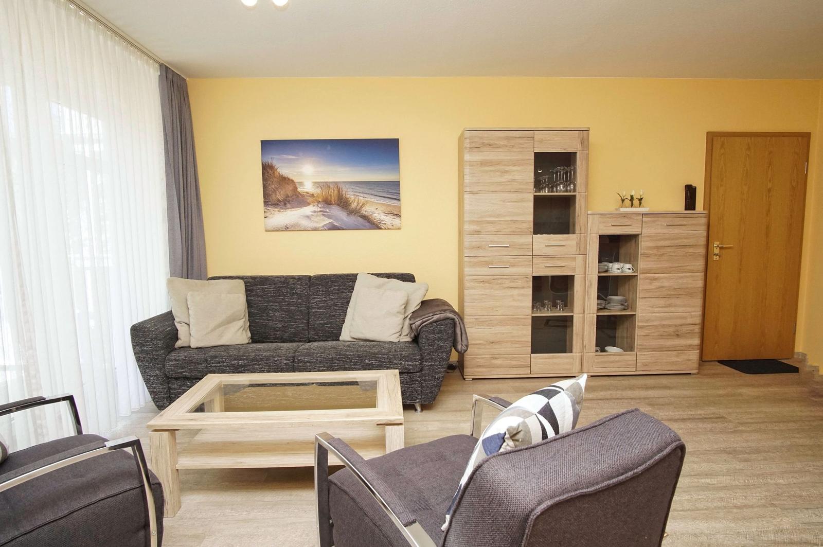 Wohnzimmer mit Sofa, Sessel und Glas-Tisch. Wandbild und Holzmöbel.