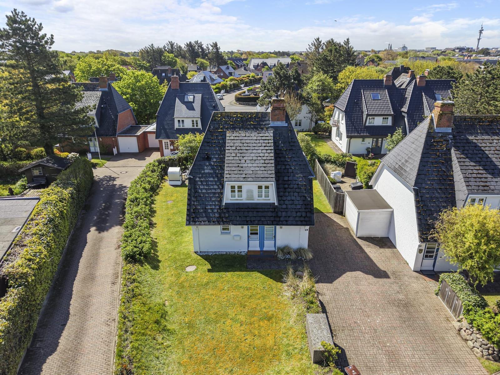Dorfhaus mit Garten und Terrasse. Umgeben von Bäumen und gepflegten Rasenflächen.