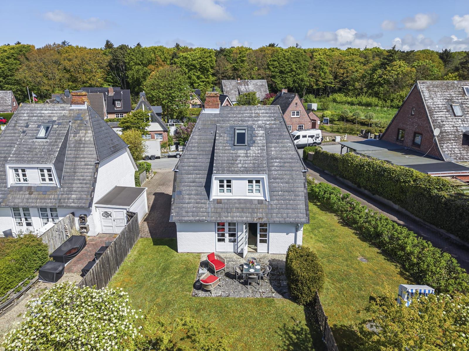 Haus mit Garten, Terrasse und Grillplatz. Umgeben von Bäumen und Nachbarhäusern.
