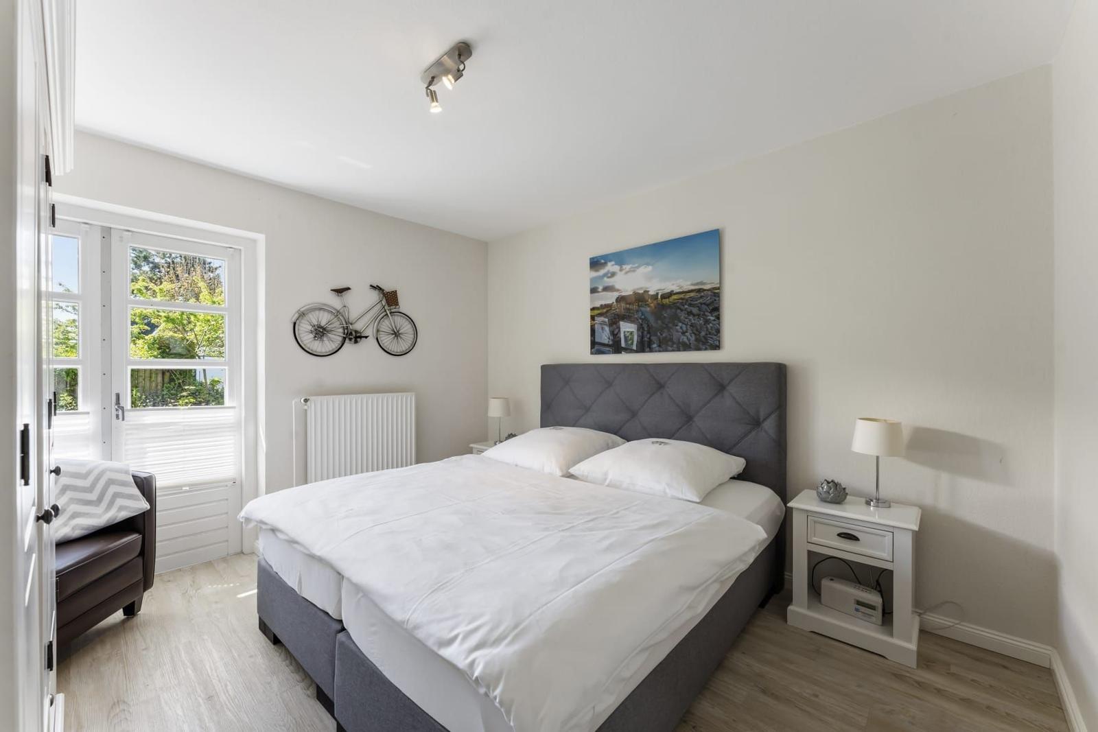 Schlafzimmer mit Doppelbett, Nachttisch und Fenster zur grünen Aussicht.