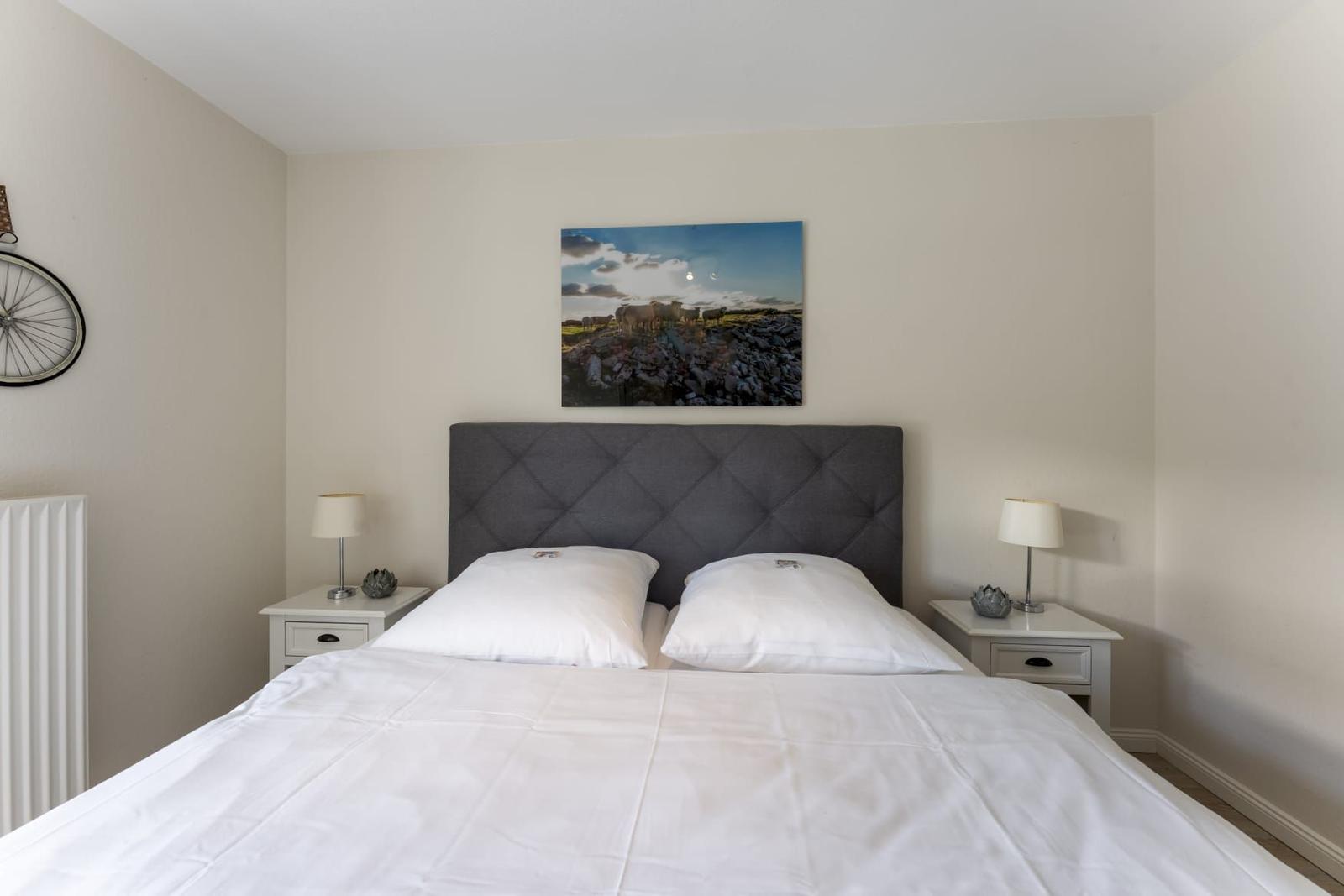 Schlafzimmer mit Doppelbett, zwei Nachttischen und Wandbild.