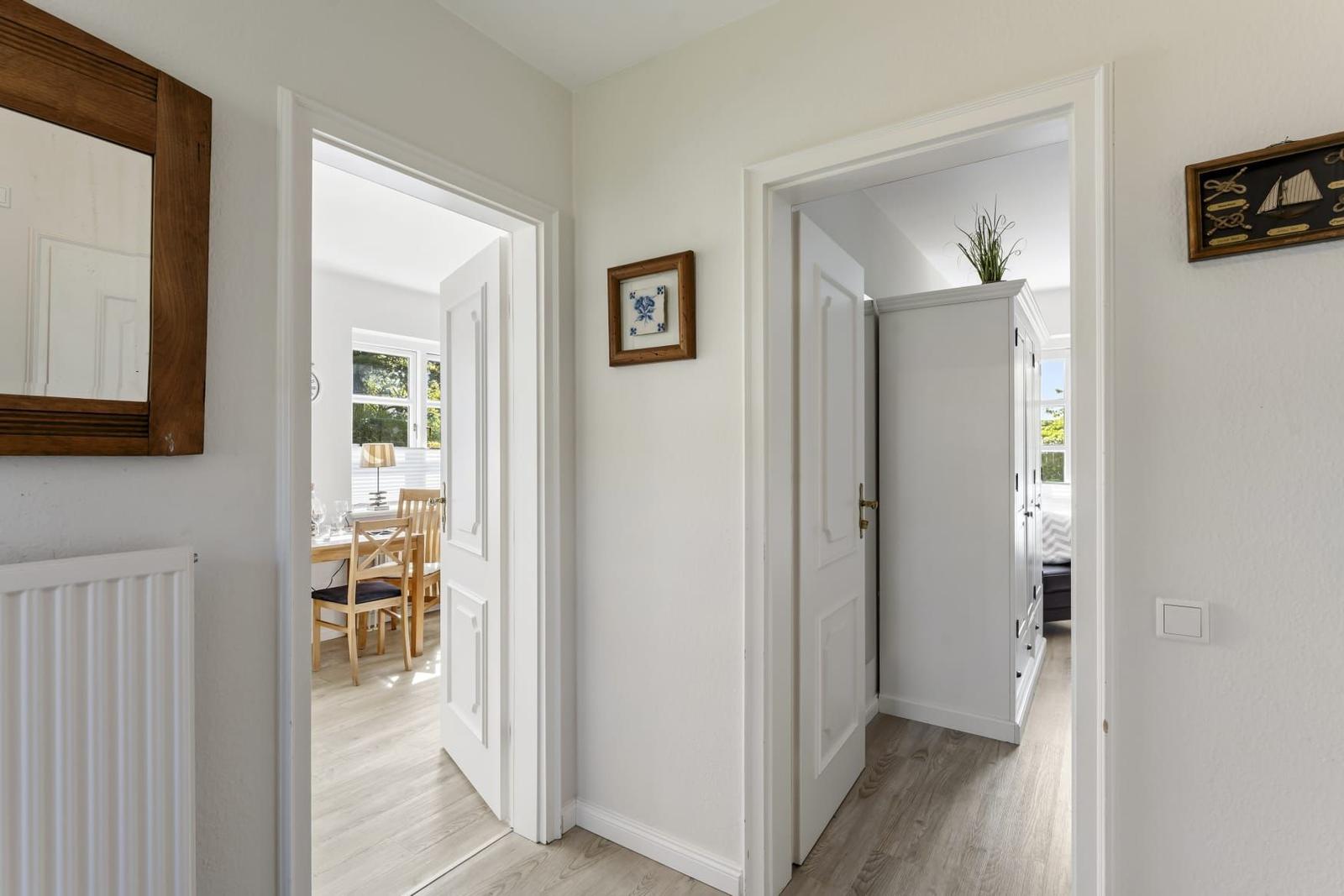 Hausflur mit Türen zu Esszimmer und Schlafzimmer, Wanddekoration und Holzboden.