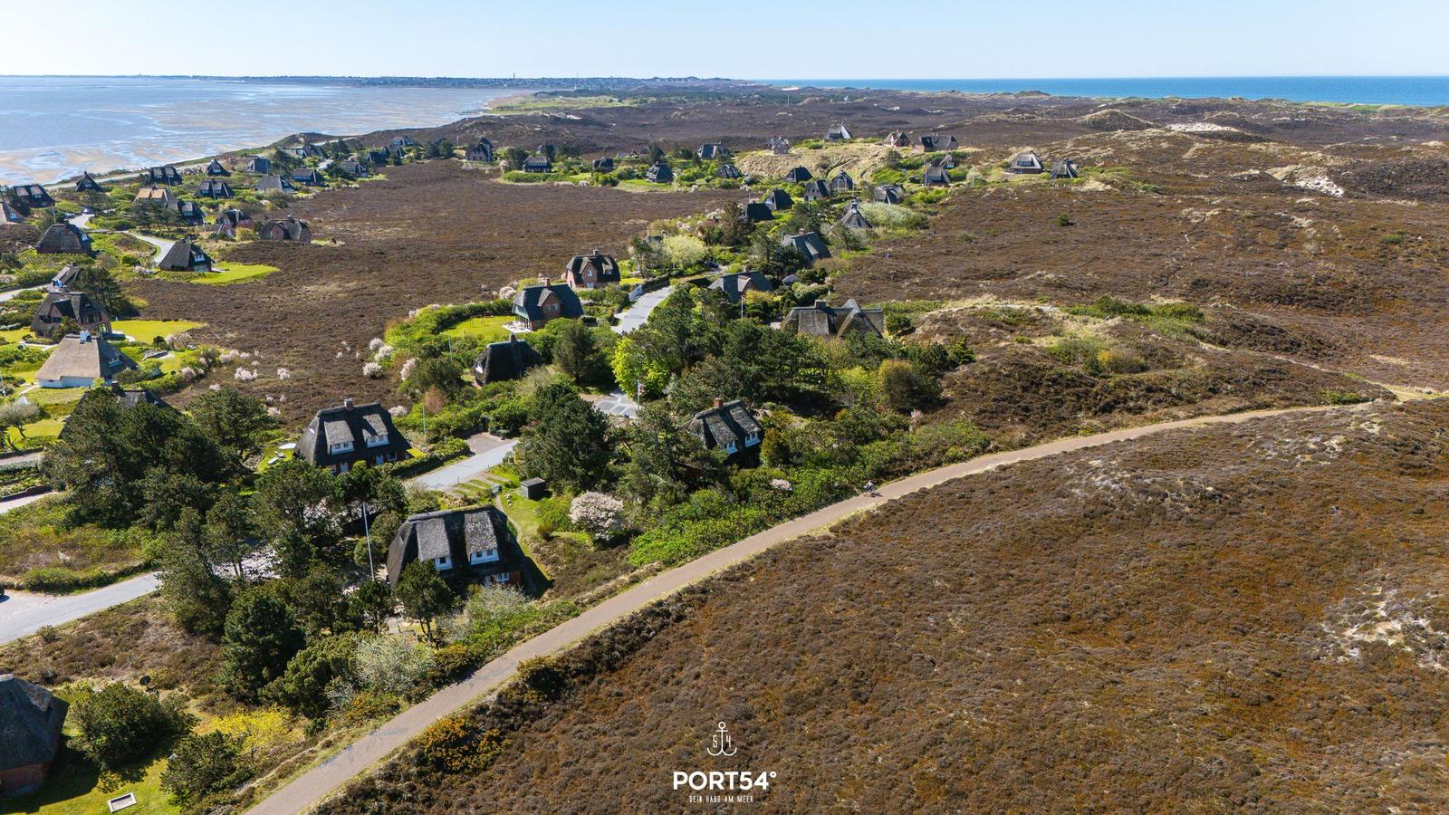 Aerial view of holiday homes on heathland near the sea.