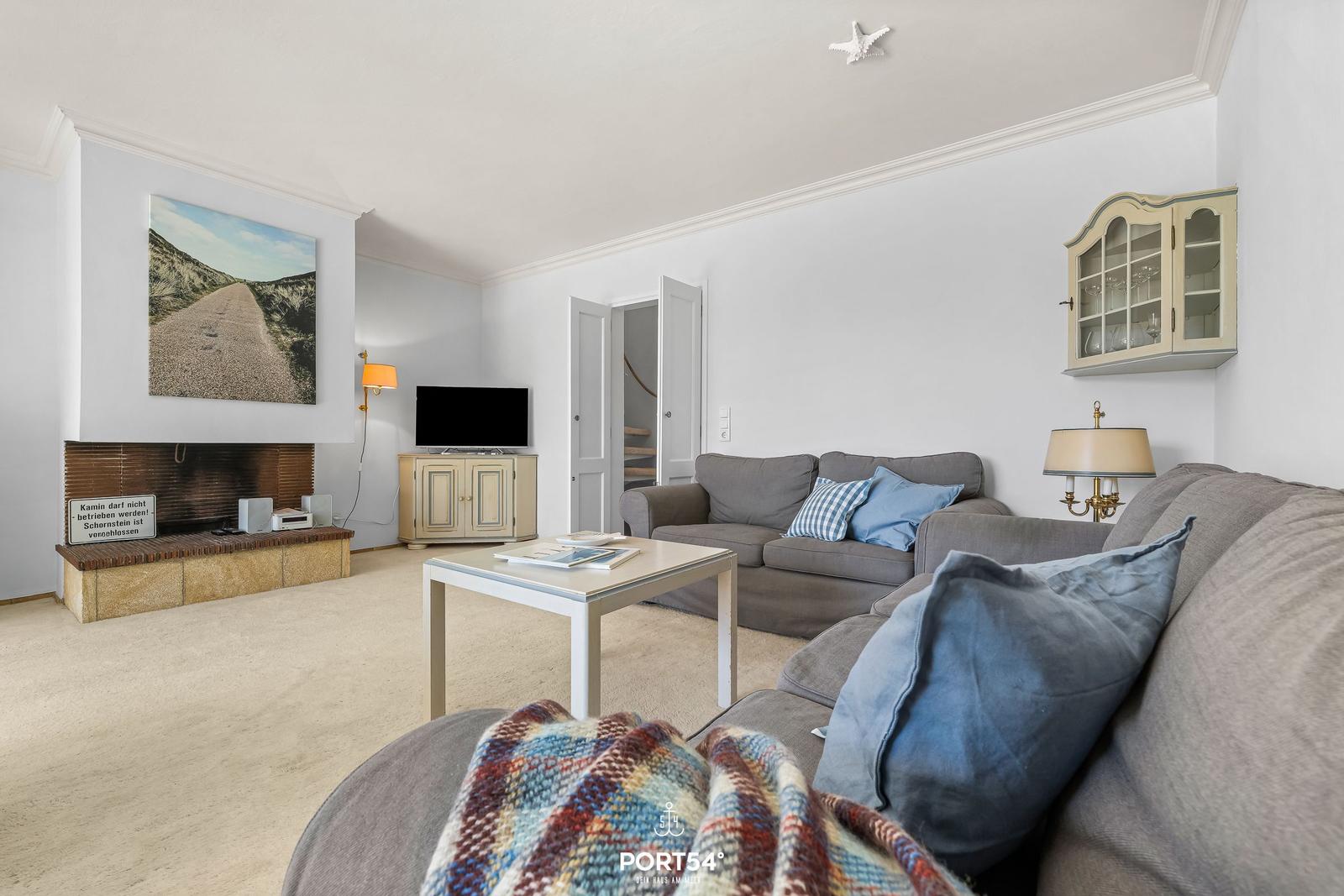 Wohnzimmer mit Sofa, Couchtisch und Kamin. An der Wand hängt ein Bild.